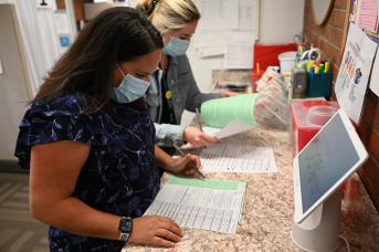 Nurses in mask stare at records